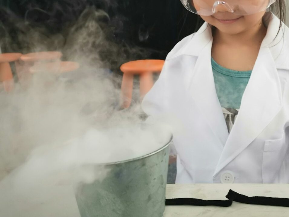 a little girl wearing a white lab coat and goggles